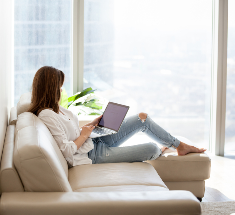 Relaxed woman using laptop in luxury home living room with big window