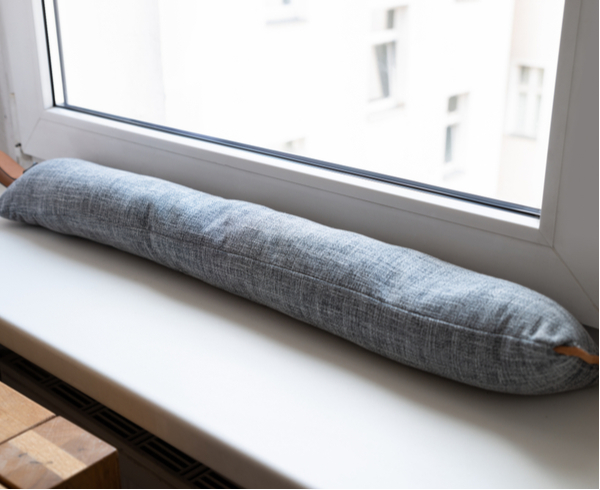 Draft excluder under window blocking cold air from traveling around